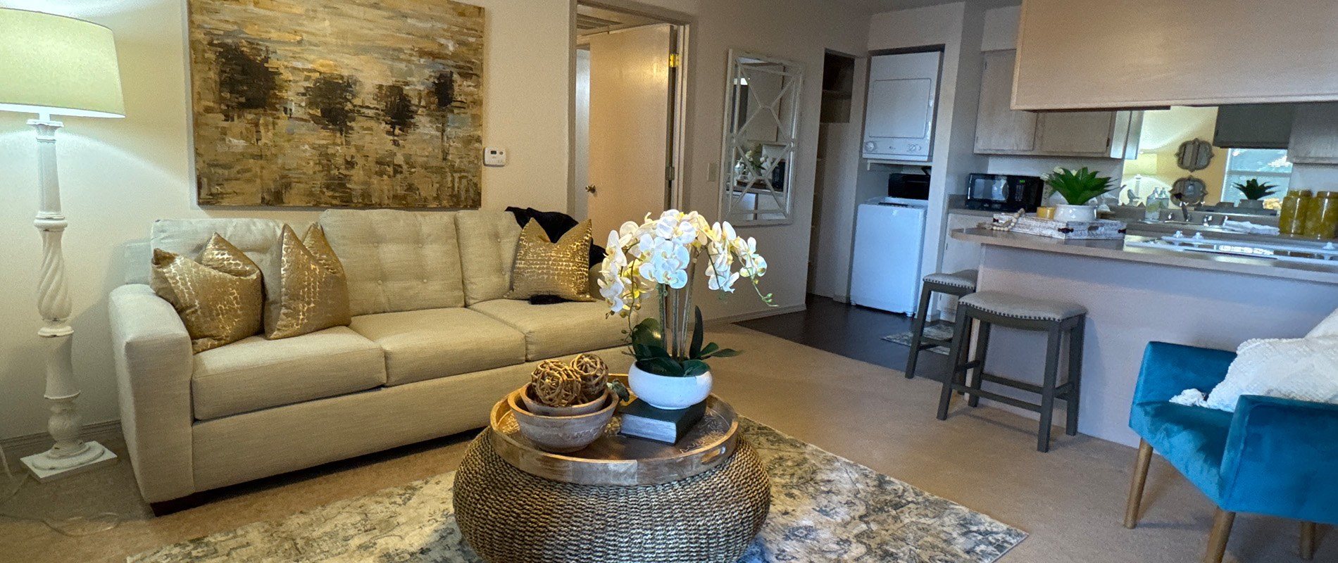 A living room with a beige couch and a large painting on the wall.